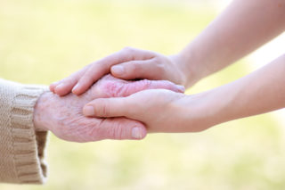 A picture of a pair of younger hands holding an older hand